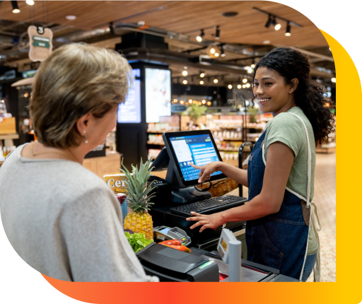 A cashier and customer at a grocery store checkout, with items ready for purchase.